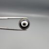 Multi-angle macro photographs of a 5.87-carat natural African Black Eye Agate (Sulemani Aqeeq) held in steel gem tweezers, showcasing a high round cabochon dome with concentric black and stark white banding, a brownish-black core pupil, and a base revealing dendritic veins.