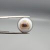 Multi-angle macro photographs of a 12.93-carat natural African Black Eye Agate (Sulemani Aqeeq) held in gem tweezers, showcasing a high round cabochon dome with sharp concentric white and brown banding, a dark brown core pupil, and a base showing natural chalcedony matrix patterns.