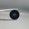 Multi-angle macro photographs of a 12.60-carat natural African Eye Agate (Sulemani Aqeeq) held in gem tweezers, showcasing a high round cabochon dome with concentric white, grey, and jet-black banding, a brownish-grey core pupil, and a polished black base with a subtle light halo center.