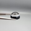 Multi-angle macro photographs of a 14.77-carat natural African Eye Agate (Sulemani Aqeeq) held in gem tweezers, showing a high round cabochon dome with a deep onyx-black core, sharp white outer ringing, tiered side profile bands, and a flat jet-black base with fine white agate pinstripes.