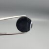 Multi-angle macro photographs of a 14.77-carat natural African Eye Agate (Sulemani Aqeeq) held in gem tweezers, showing a high round cabochon dome with a deep onyx-black core, sharp white outer ringing, tiered side profile bands, and a flat jet-black base with fine white agate pinstripes.