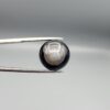 Multi-angle macro photographs of a 13.29-carat natural African Banded Eye Agate (Sulemani Aqeeq) held in gem tweezers, displaying a high round cabochon dome with concentric white and grey ringing around a translucent light core, a black border, and a reverse side showing undulating blue-grey wave banding.