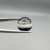 Multi-angle macro photographs of an 8.02-carat natural African Banded Eye Agate (Sulemani Aqeeq) held in steel gem tweezers, displaying a high round cabochon dome with wavy concentric white and earth-brown banding around a deep black core, crisp side fortification layers, and a flat jet-black base.