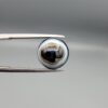 Multi-angle macro photographs of a 6.94-carat natural African Banded Eye Agate (Sulemani Aqeeq) held in gem tweezers, displaying a high round cabochon dome with complex concentric white and brown fortification rings around a deep black core, tiered profile layers, and a polished flat black base.