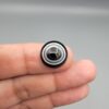 Multi-angle macro photographs of a 14.55-carat natural African Banded Eye Agate (Sulemani Aqeeq) held on fingers, showcasing a high round cabochon dome with sharp concentric white and black fortification rings framing a deep black pupil core, and a smooth jet-black base.