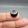 Multi-angle macro photographs of a 14.55-carat natural African Banded Eye Agate (Sulemani Aqeeq) held on fingers, showcasing a high round cabochon dome with sharp concentric white and black fortification rings framing a deep black pupil core, and a smooth jet-black base.