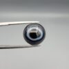 Multi-angle macro photographs of a 13.11-carat natural African Banded Eye Agate (Sulemani Aqeeq) held in gem tweezers, displaying a high round cabochon dome with crisp concentric white fortification rings around a deep black pupil core, dramatic side profile banding, and a reverse base showcasing a bold white-and-grey crescent wave pattern.