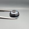 Multi-angle macro photographs of a 13.11-carat natural African Banded Eye Agate (Sulemani Aqeeq) held in gem tweezers, displaying a high round cabochon dome with crisp concentric white fortification rings around a deep black pupil core, dramatic side profile banding, and a reverse base showcasing a bold white-and-grey crescent wave pattern.