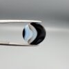 Multi-angle macro photographs of a 13.11-carat natural African Banded Eye Agate (Sulemani Aqeeq) held in gem tweezers, displaying a high round cabochon dome with crisp concentric white fortification rings around a deep black pupil core, dramatic side profile banding, and a reverse base showcasing a bold white-and-grey crescent wave pattern.