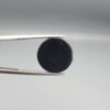 Macro photographs of an 11.69-carat natural African Banded Eye Agate (Sulemani Aqeeq) held in steel gem tweezers, displaying a high round cabochon dome with a deep onyx-black body centered by a luminous blue-grey eye motif, and a polished flat black base.