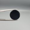 Multi-angle macro photographs of a 13.83-carat natural African Banded Eye Agate (Sulemani Aqeeq) held in steel gem tweezers, showcasing a high round cabochon dome with a luminous translucent ice-blue central eye field, framed by a deep black margin, and a smooth jet-black flat reverse base.