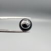 Multi-angle macro photographs of a 7.14-carat natural African Banded Eye Agate (Sulemani Aqeeq) shown in gem tweezers and on fingertips, featuring a high round cabochon dome with a deep black body accented by a sharp teardrop-shaped concentric white and black ring pattern forming a distinct central eye motif, and a solid uniform black reverse base with minor edge wear.