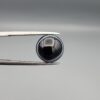 Multi-angle macro photographs of a 5.97-carat natural African Banded Eye Agate (Sulemani Aqeeq) held in gem tweezers, showing a top view with a dominant black body framed by a sharp white arc, a profile view with a distinct V-shaped white fortification band, and a reverse view revealing a multi-eye cellular pattern in blue-grey and black.