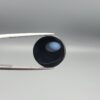 Multi-angle macro photographs of a 12.13-carat natural African Banded Eye Agate (Sulemani Aqeeq) held in steel gem tweezers, showcasing a top view with a mirror-polished deep black body bordered by a fine white ring, a side profile displaying lower white flank banding, and a reverse view revealing a unique luminous blue-grey eye motif on a flat black field.