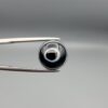 Multi-angle macro photographs of a 6.29-carat natural African Banded Eye Agate (Sulemani Aqeeq) held in steel gem tweezers, showcasing a top view with a central black pupil enclosed by a crisp white halo ring, a profile view displaying lower flank fortification bands, and a reverse view revealing a flat translucent milky-grey gradient base.