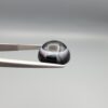 Multi-angle macro photographs of an 8.57-carat natural African Banded Eye Agate (Sulemani Aqeeq) held in steel gem tweezers, showcasing a top view with a crisp concentric outer white ring framing a deep black core, a side profile displaying high-dome geometry and layered fortification pinstripes, and a reverse view of a flat, solid mirror-polished black base.