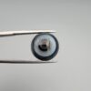 Multi-angle macro photographs of an 8.35-carat natural African Banded Eye Agate (Sulemani Aqeeq) held in steel gem tweezers, showcasing a top view with concentric black, grey, and white rings framing a luminous core, a side profile displaying smooth high-dome geometry with layered fortification bands, and a reverse view of a flat, dark mottled base with a nebulous center.