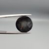Multi-angle macro photographs of an 8.35-carat natural African Banded Eye Agate (Sulemani Aqeeq) held in steel gem tweezers, showcasing a top view with concentric black, grey, and white rings framing a luminous core, a side profile displaying smooth high-dome geometry with layered fortification bands, and a reverse view of a flat, dark mottled base with a nebulous center.