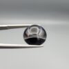 Multi-angle macro photographs of a 7.64-carat natural African Banded Eye Agate (Sulemani Aqeeq) held in steel gem tweezers, showcasing a top view with a sharp concentric ring and lower translucent band, a side profile displaying smooth high-dome geometry with horizontal flank fortification, and a reverse view of a flat black base featuring a striking horizontal banded division.