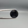 Multi-angle macro photographs of a 5.89-carat natural African Banded Eye Agate (Sulemani Aqeeq) held in steel gem tweezers, displaying a top view with a crisp concentric white ring framing a dark brownish-black central core, and a reverse view revealing a flat, dark mottled chalcedony base with subtle natural edge inclusions.