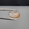 High-resolution macro photographs of a 14.26-carat natural Rutilated Quartz (Moh-e-Najaf) held in steel tweezers, displaying a brilliant oval cut, exceptional water-clear crystal matrix, and natural internal reddish-orange hematite platelets with fine scattered rutile needles sourced from Najaf Al-Ashraf, Iraq.