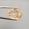 High-resolution macro photographs of a 17.27-carat natural Rutilated Quartz (Moh-e-Najaf) held in steel tweezers, displaying a finely faceted oval silhouette, water-clear crystal body, and rich internal golden-brown hematite platelets with contrasting dark rutile needles sourced from Najaf Al-Ashraf, Iraq.