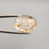 High-resolution macro photographs of a 17.27-carat natural Rutilated Quartz (Moh-e-Najaf) held in steel tweezers, displaying a finely faceted oval silhouette, water-clear crystal body, and rich internal golden-brown hematite platelets with contrasting dark rutile needles sourced from Najaf Al-Ashraf, Iraq.
