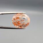 High-resolution macro photographs of an 8.52-carat natural Rutilated Quartz (Moh-e-Najaf) held in steel tweezers, showcasing a brilliant oval facet cut, exceptional crystal clarity, and a dynamic internal weave of coppery orange-red hematite platelets interspersed with fine rutile needles sourced from Najaf Al-Ashraf, Iraq.