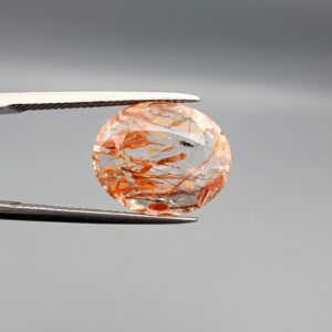 High-resolution macro photographs of an 8.52-carat natural Rutilated Quartz (Moh-e-Najaf) held in steel tweezers, showcasing a brilliant oval facet cut, exceptional crystal clarity, and a dynamic internal weave of coppery orange-red hematite platelets interspersed with fine rutile needles sourced from Najaf Al-Ashraf, Iraq.