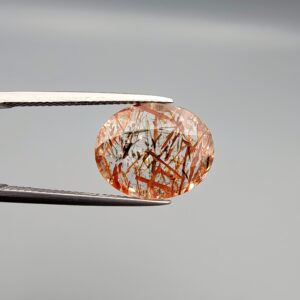 High-resolution macro photographs of a 7.20-carat natural Rutilated Quartz (Moh-e-Najaf) held in steel tweezers, displaying a brilliant oval facet cut, water-clear crystal clarity, and a dramatic internal network of crisscrossing copper-red blades with contrasting dark rutile needles sourced from Najaf Al-Ashraf, Iraq.