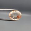 High-resolution macro photographs of a 14.39-carat natural Rutilated Quartz (Moh-e-Najaf) held in steel gem tweezers, displaying a brilliantly faceted oval cut, water-clear crystal body, fine golden rutile needles, and a focal concentrated orange-red hematite inclusion cluster sourced from Najaf Al-Ashraf, Iraq.
