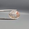 High-resolution macro photographs of a 14.39-carat natural Rutilated Quartz (Moh-e-Najaf) held in steel gem tweezers, displaying a brilliantly faceted oval cut, water-clear crystal body, fine golden rutile needles, and a focal concentrated orange-red hematite inclusion cluster sourced from Najaf Al-Ashraf, Iraq.