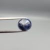 High-resolution macro photographs of a 5.40-carat natural Afghan Blue Indigo Sapphire (Neelam) held in steel gem tweezers, showcasing a masterfully faceted oval silhouette, deep midnight indigo-blue body color, and natural internal corundum silk structures sourced from Afghanistan.