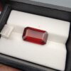 High-resolution macro photographs of a 9.59-carat natural Hessonite Garnet (Gomed) resting on a white leather display cushion inside a black leatherette gem box, displaying an emerald step-cut rectangular silhouette, rich reddish-brown to warm honey-amber color, and characteristic internal heat-wave swirl effect (treacle).