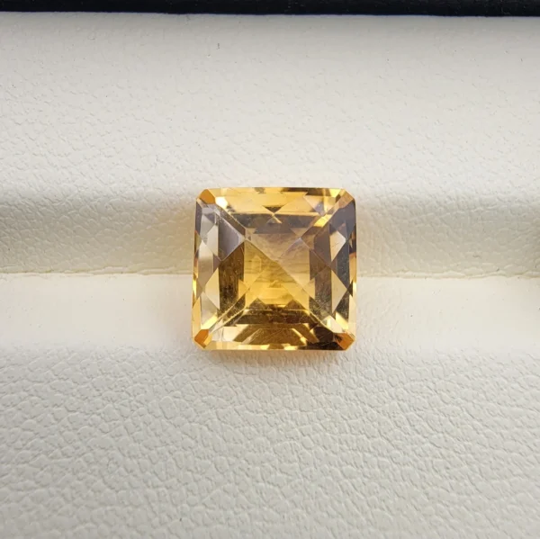 High-resolution macro photographs showing a 4.22-carat natural Citrine Quartz (Sunela) octagon step cut gemstone displayed in a luxury white-padded display box, exhibiting luminous golden-yellow saturation, eye-clean clarity, and crisp step-cut facets.