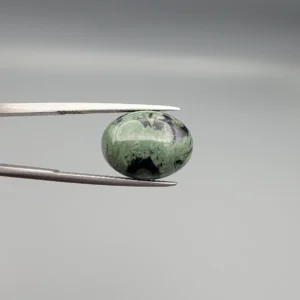 High-resolution macro photographs showing a 10.00-carat natural Serpentine (Zehr Mora) oval cabochon held in gemological tweezers from front and back views, displaying a sage-green body matrix with striking black mineral inclusions and veining under a smooth dome polish.
