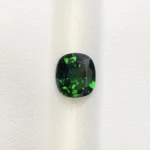 High-resolution scan of an official GGI (Galaxy Gemological Institute) Gemstone Report for a 1.48-carat Natural Chrome Green Tourmaline sourced from Tanzania, detailed with certificate number KHI2610280448, cushion mixed cut dimensions (7.77 x 6.94 x 4.33 mm), transparent green color, and QR verification code.