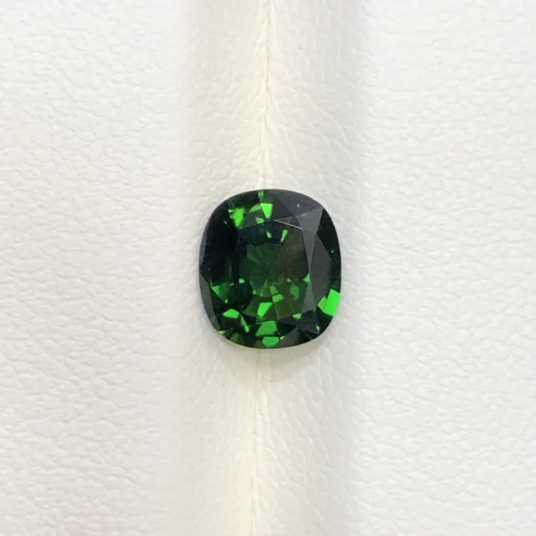 High-resolution scan of an official GGI (Galaxy Gemological Institute) Gemstone Report for a 1.48-carat Natural Chrome Green Tourmaline sourced from Tanzania, detailed with certificate number KHI2610280448, cushion mixed cut dimensions (7.77 x 6.94 x 4.33 mm), transparent green color, and QR verification code.