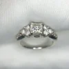 Multi-angle macro photographs of a 14K white gold 7-stone diamond engagement ring held against a white fabric backdrop, featuring a central natural cushion-cut diamond flanked by six graduated round brilliant-cut diamonds across the gallery band.