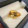 High-resolution macro photographs showing an 8.32-carat natural Citrine Quartz (Sunela) pear cut faceted gemstone set in a white display box, showcasing intense golden-amber saturation, eye-clean clarity, and brilliant light dispersion.