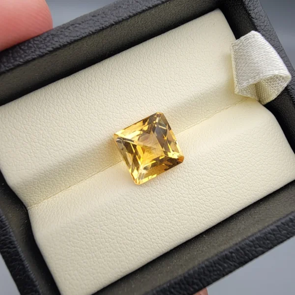 High-resolution macro photographs showing a 4.22-carat natural Citrine Quartz (Sunela) octagon step cut gemstone displayed in a luxury white-padded display box, exhibiting luminous golden-yellow saturation, eye-clean clarity, and crisp step-cut facets.