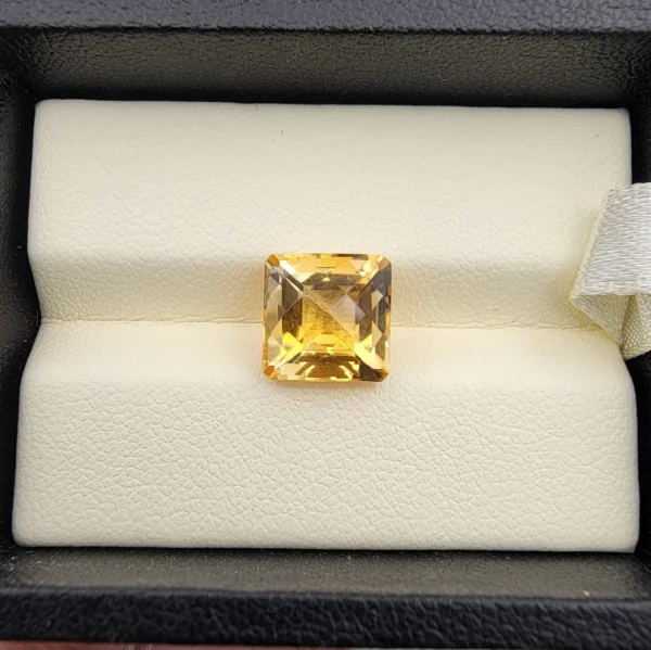 High-resolution macro photographs showing a 4.22-carat natural Citrine Quartz (Sunela) octagon step cut gemstone displayed in a luxury white-padded display box, exhibiting luminous golden-yellow saturation, eye-clean clarity, and crisp step-cut facets.