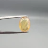 High-resolution macro photograph displaying a 3.78-carat natural Yellow Sapphire (Pukhraj) oval faceted gemstone held securely in gemological tweezers, featuring a warm golden-yellow body color, natural crystal inclusions, and brilliant facet architecture.