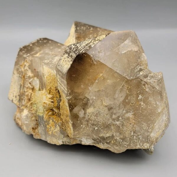 High-resolution macro photographs showcasing a monumental 2,318-gram natural Smoky Quartz multi-crystal cluster specimen from Pakistan, featuring fully formed translucent smoke-tea quartz prisms with sharp pyramidal terminations, natural earthy mineral coatings, and white feldspar matrix accents.
