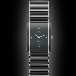 Studio product photograph of a luxury Rado Integral Jubilé Swiss watch featuring a rectangular black ceramic dial with diamond indices, date window, and a matching black-and-silver ceramic link bracelet against a dark gradient backdrop.
